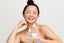 Smiling woman holding Korean28 Glass Skin Bundle featuring hyaluronic acid serum, niacinamide peach serum, and Centella cream.
